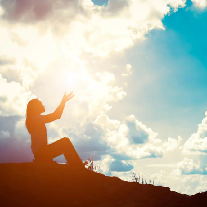 A woman reaching towards the light at sunrise