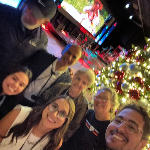 Group selfie with the team beside the stage and the Christmas tree