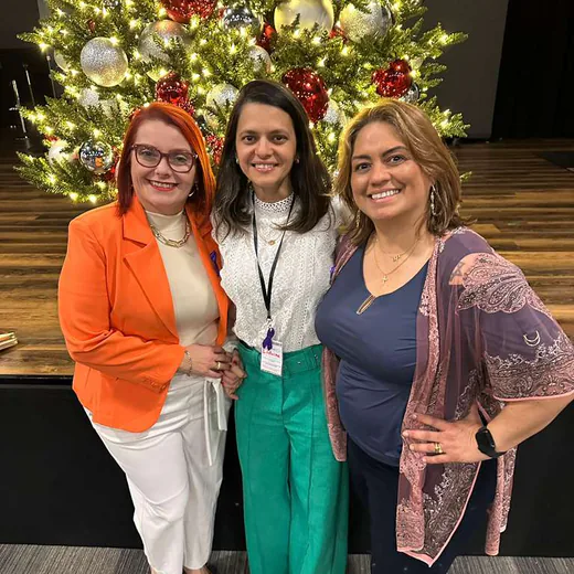 Three guests smiling in front of the Christmas tree