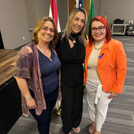 Three members of the team in front of the flags beside the stage