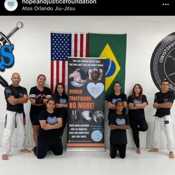 The training group beside a banner reading “Human trafficking no more”, with the U.S. and Brazilian flags